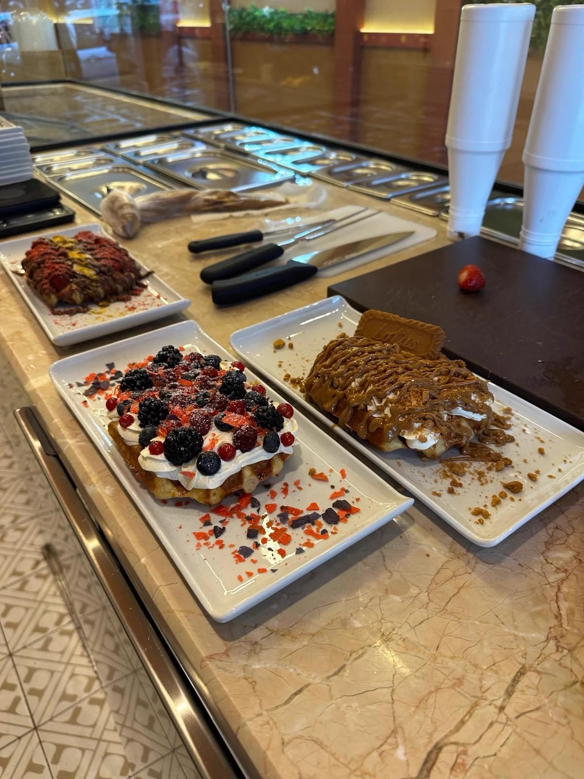 Tezgâhta hazırlanmış çilekli, orman meyveli ve Lotus waffle tabakları