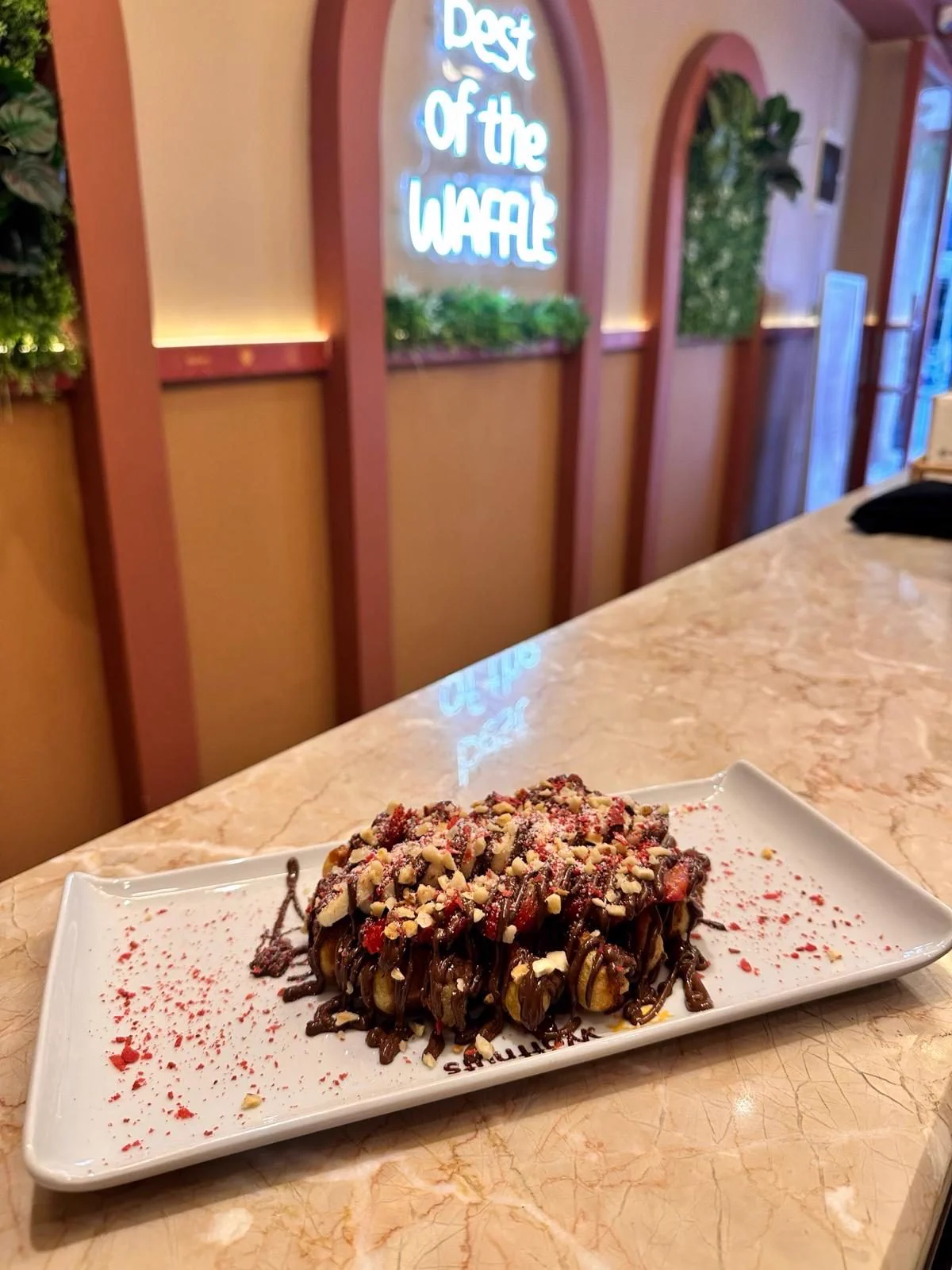 Neon tabelanın altında çikolata soslu fındıklı waffle